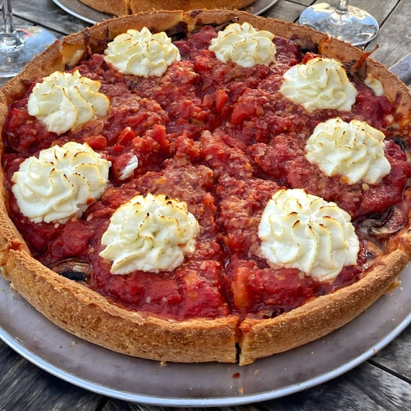 Deep-dish pizza from The Underground Pizza, topped with chunky red sauce and dollops of white cheese.